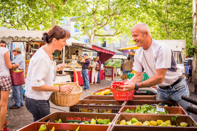 Une dame achète ces fruits et légumes à un maraicher sur le marché