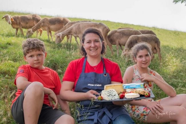 Femme asise dans l'herbetenant en plateaux de fromage , enfants et brebis